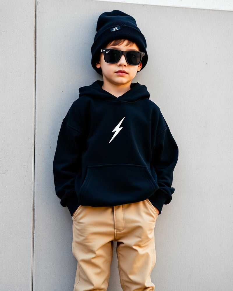 Boy in oversized black bolt hoodie with beanie and sunglasses on concrete wall