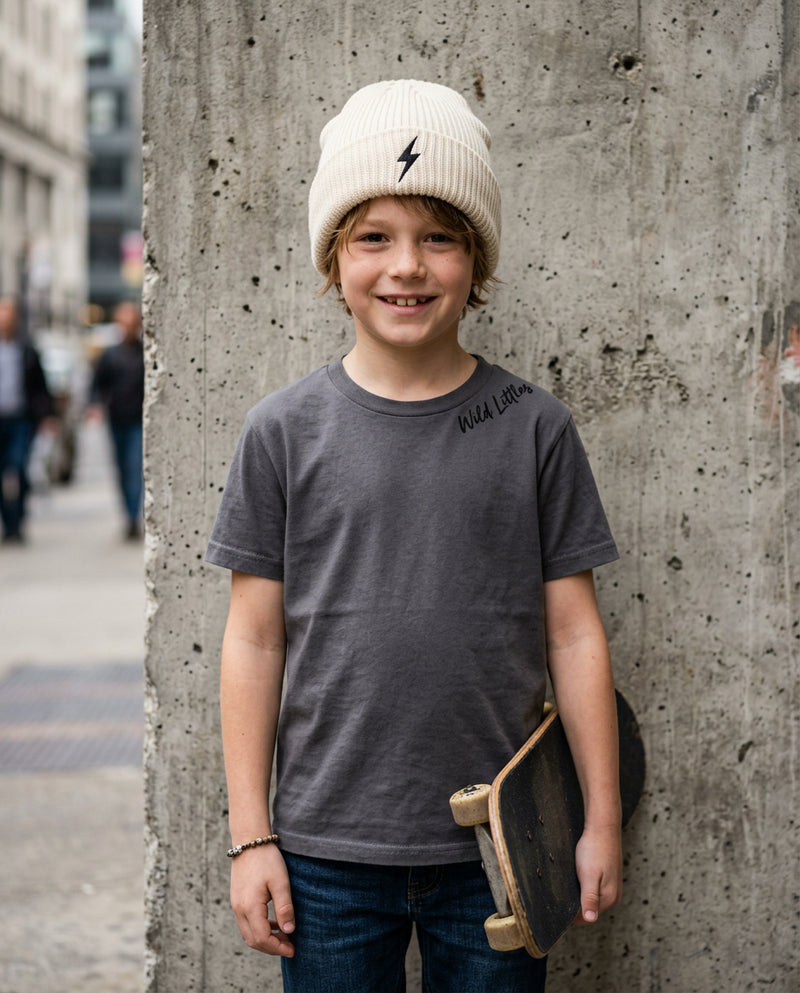 Kid wearing cream ribbed Wild Littles beanie with embroidered lightning bolt and signature script tee